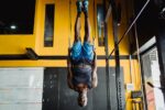 Fit man performing inversion exercises in a brightly lit gym environment.