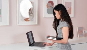 Are Standing Desks Good for Back Pain? The Evidence A businesswoman stands indoors, using a laptop, reflecting focus and professionalism.